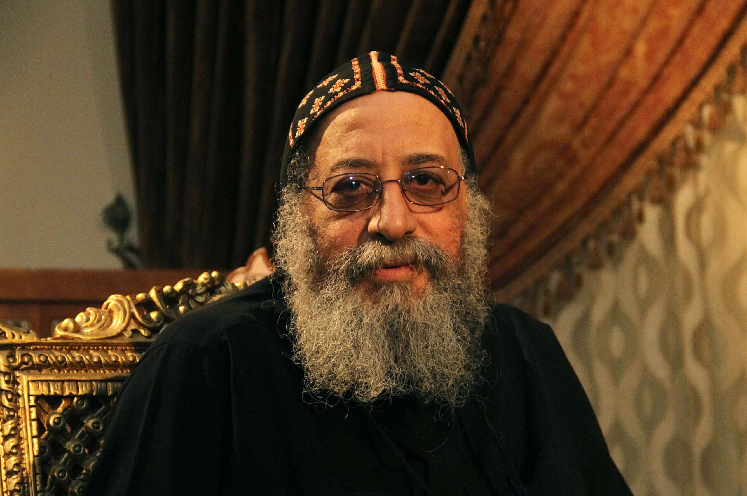 A man with long beard and glasses wearing a hat.